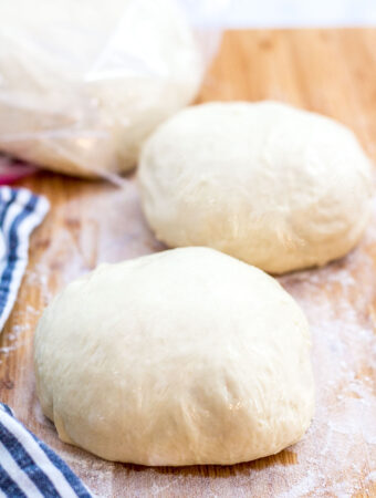 one pizza dough in a freezer bag and two smaller pizza dough on a cutting board