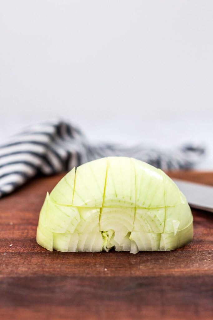 straight shot of half an onion sliced parallel and perpendicular to the cutting board