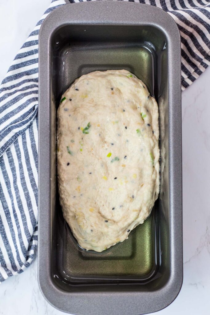 focaccia dough in a bread pan with plenty avocado oil in the bottom