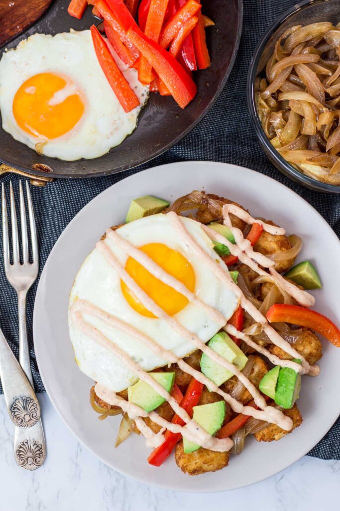 tater tot breakfast hash - air fried tater tots, avocado, sauteed pepper, caramelized onion, an fried egg, and drizzle of smoked paprika garlic aioli