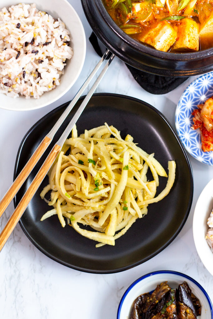 bellflower roots (doraji namul) with a bowl of rice and other Korean side dishes around it