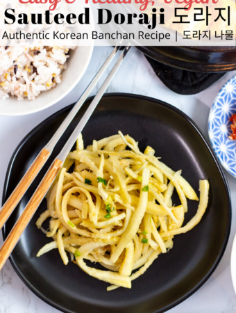 sauteed doraji on a black plate with chopsticks next to it