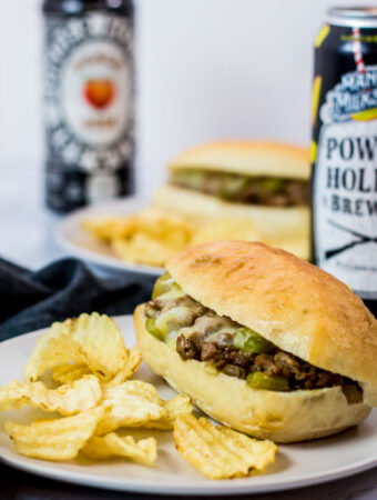 two vegetarian philly cheesesteak sloppy joe sandwiches with potato chips on the side