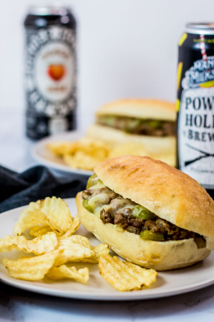 two vegetarian philly cheesesteak sloppy joes sandwiches with potato chips on the side