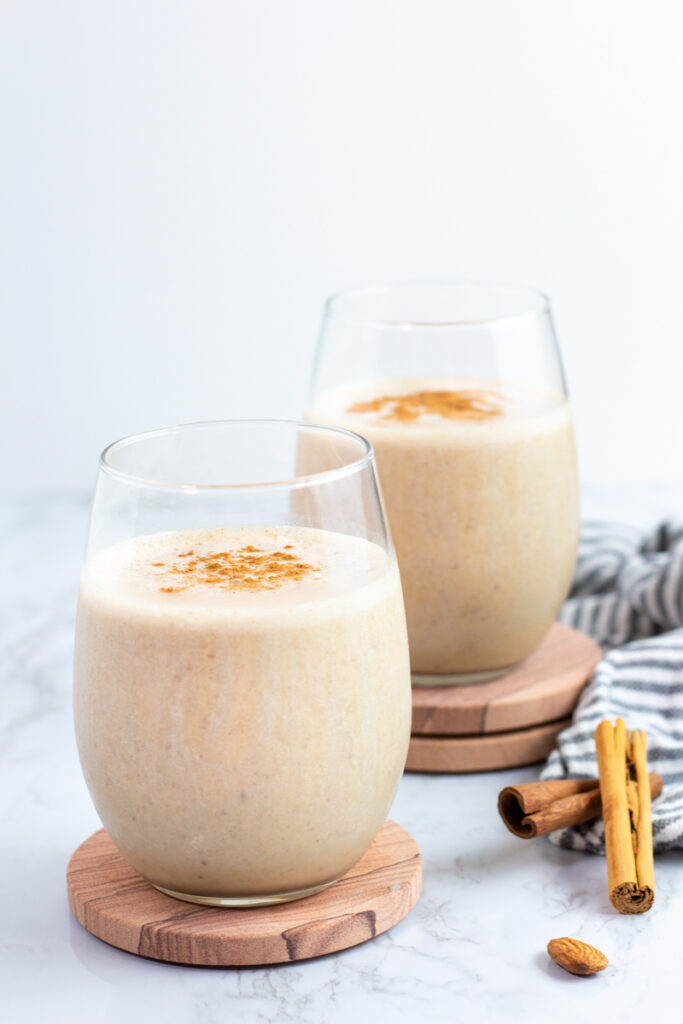 two glasses of smoothie with a sprinkle of cinnamon on top as garnish.