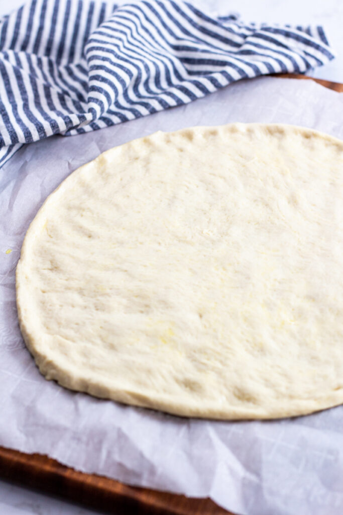 flatten circular pizza dough on the parchment paper.