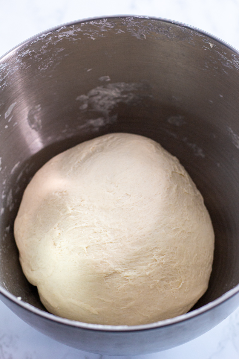 pizza dough shaped into a bowl in a stand mixer bowl.