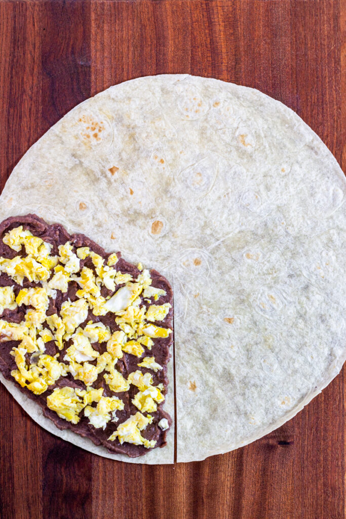 scrambled egg on top of refried bean on a tortilla.