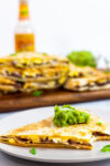 A piece of breakfast quesadilla with guacamole on top.