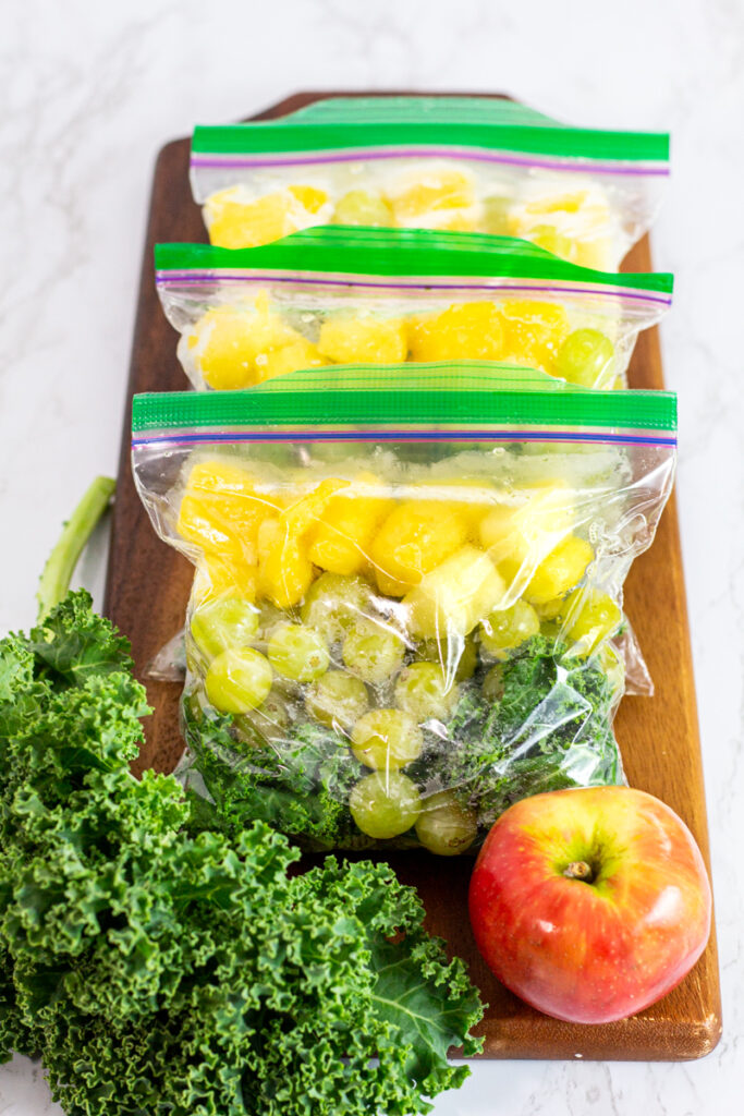 portioned out kale, grapes, and pineapple in freezer safe bags.