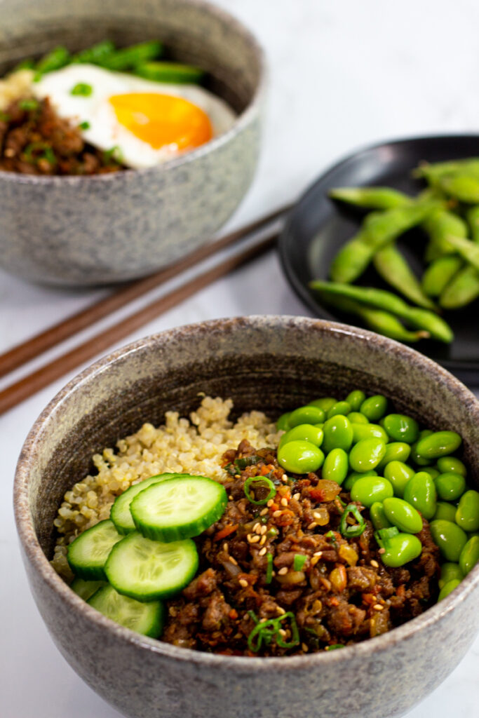 two bulgogi buddha bowls - one with fried egg on top (for vegetarian) and one with edamame (for vegan).