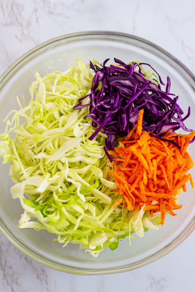 cabbage and grated carrot in a clear bowl.