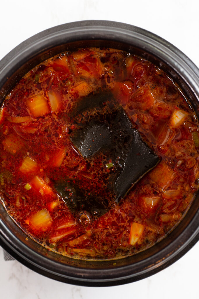 Water and kombu are added to the soup in a clay pot.