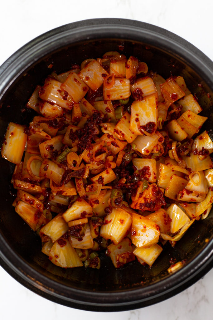 onion is added to the red pepper oil with green onion to the clay pot.