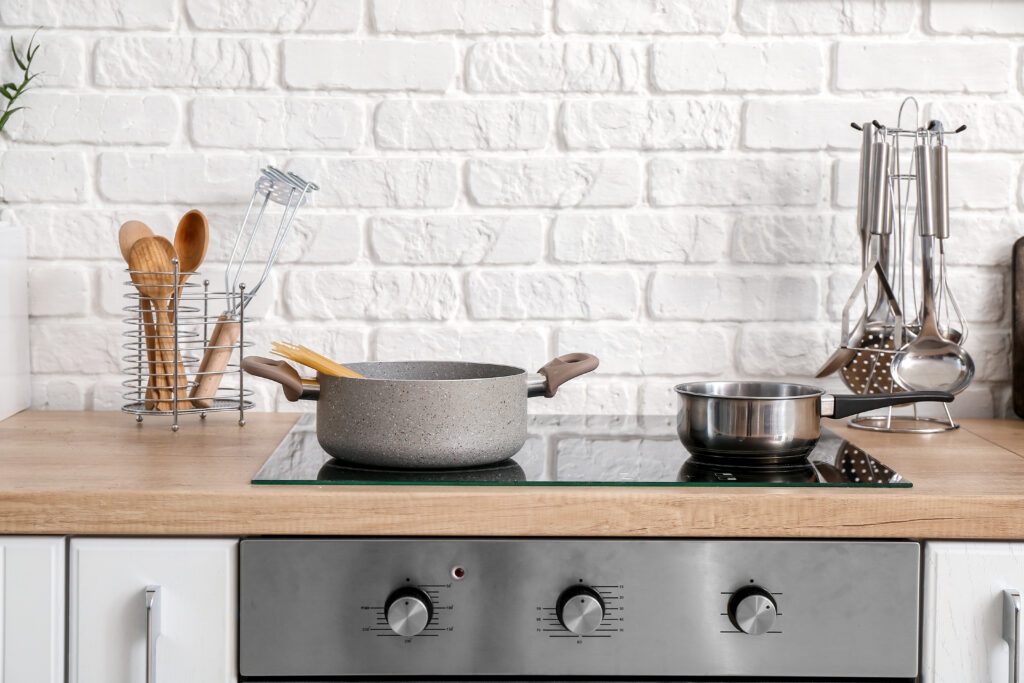 Pots on the stovetop in the kitchen with some utensils in the background.