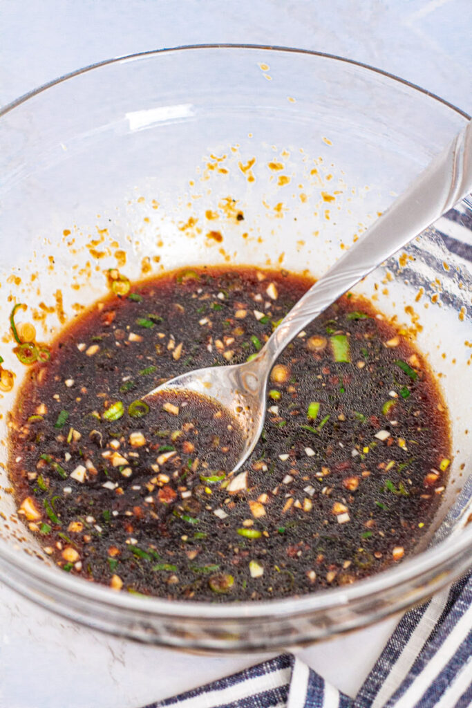 Soy sauce based marinade in a clear bowl with a spoon
