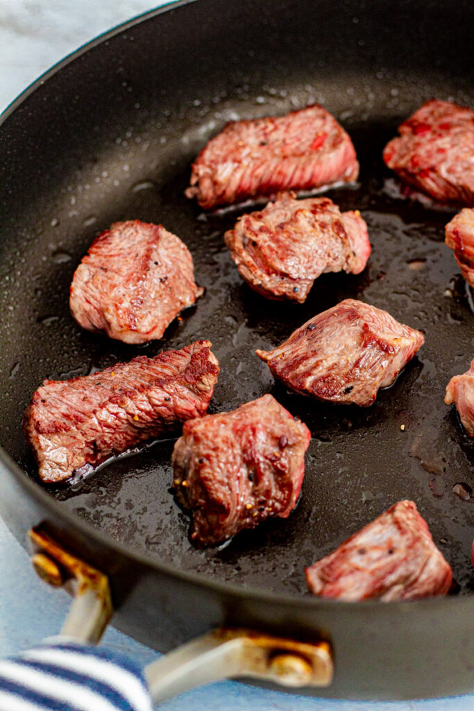 Seared beef chunks in the pan.