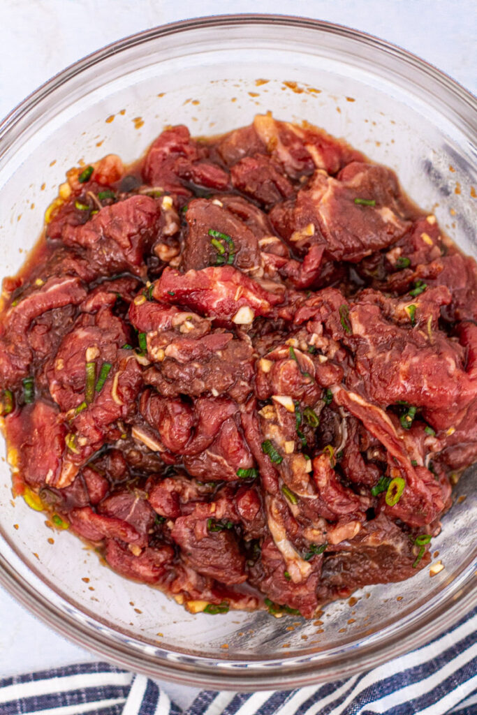 Sliced beef marinating in the  marinade in a clear bowl