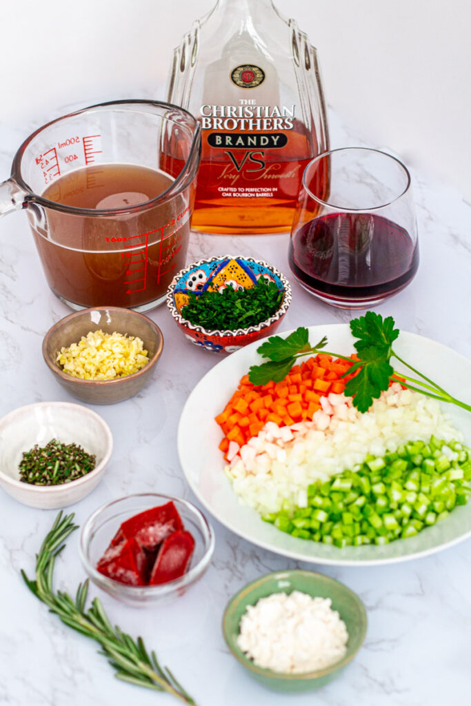 Ingredients for the dish - brandy, beef broth, red wine, parsley, minced garlic, rosemary, tomato paste, flour, carrots, onions, and celery.