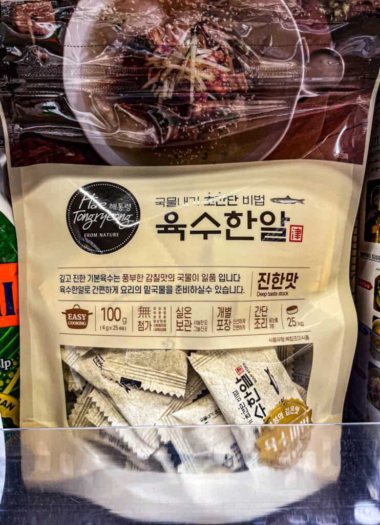 A beige package of soup stock with individual soup coin inside, designed for easy cooking and deep umami broth flavor