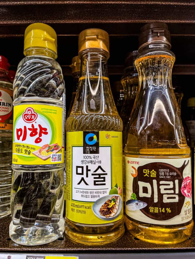 Close-up of Korean cooking wine bottles from Ottogi, Daesang, and Lotte brands, labeled as Matsul and Mirim