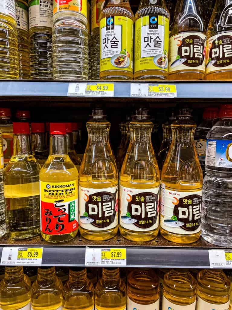 Grocery shelf filled with Korean cooking wines like Lotte Mirim and Daesang Matsul