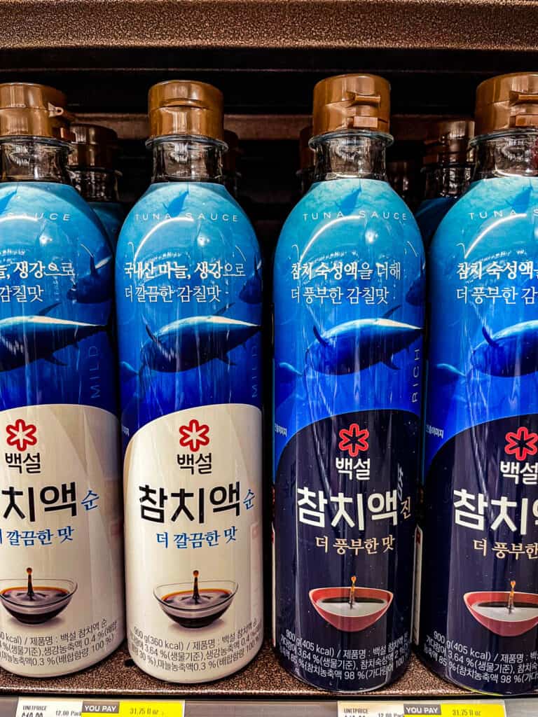 Close-up of Baeksul brand tuna fish sauce bottles in blue packaging for Korean cooking