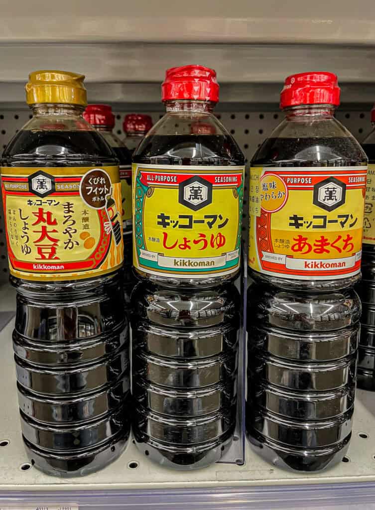 Close-up of three Kikkoman soy sauce bottles in different varieties, labeled as all-purpose Japanese seasonings.