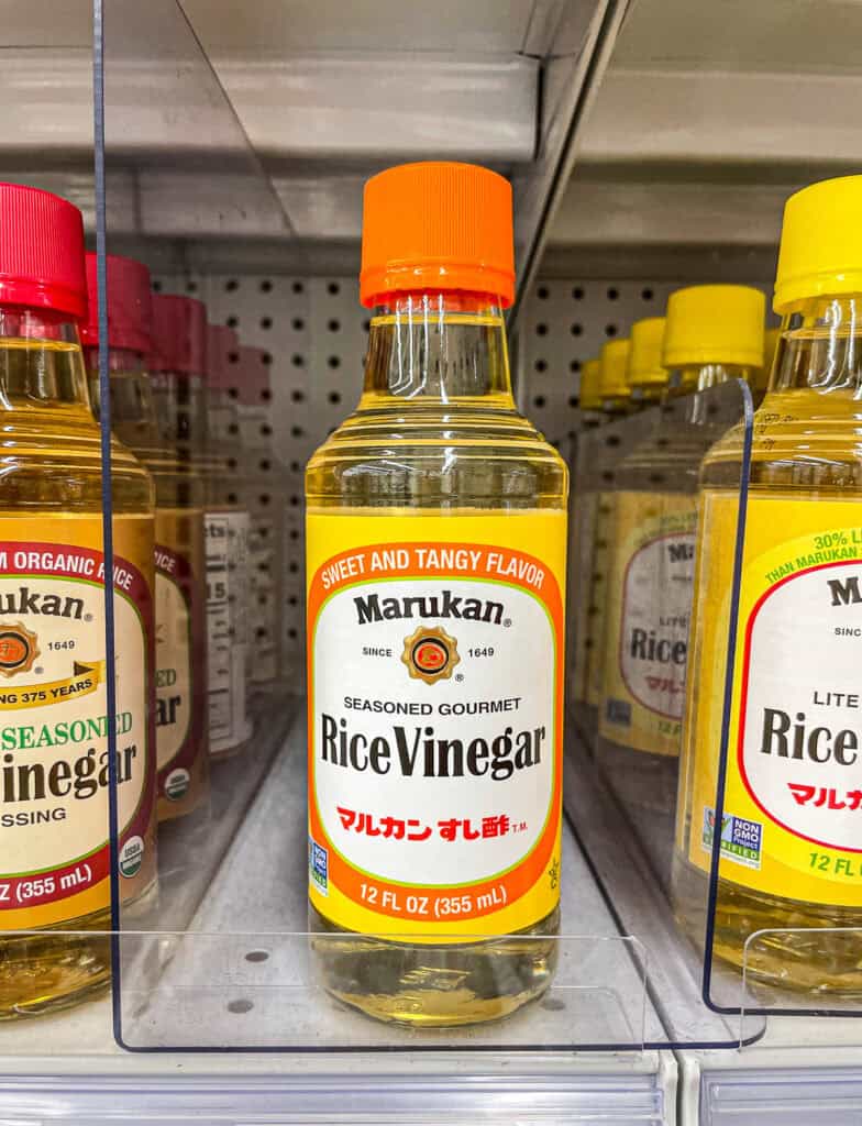 Close-up of a bottle of Marukan seasoned gourmet rice vinegar on a grocery store shelf, used in Japanese cooking and sushi rice.
