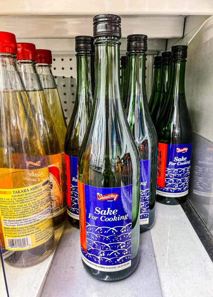 Close-up of Shirakiku brand sake for cooking bottles on a grocery store shelf, used in Japanese sauces and marinades.