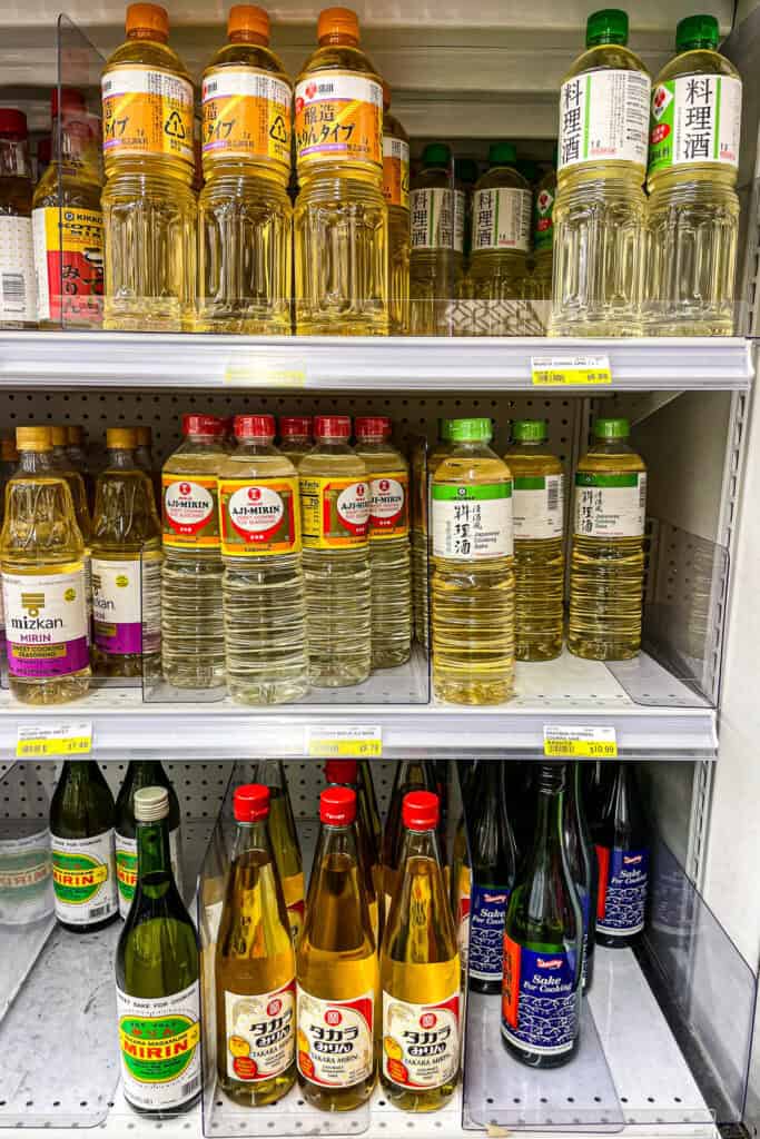Bottles of mirin sweet rice seasoning displayed on a grocery store shelf, a key ingredient in Japanese sauces, glazes, and marinades.
