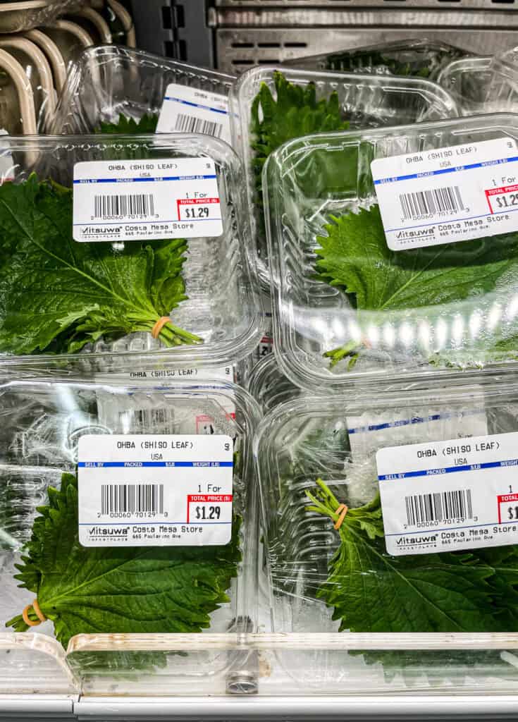 Packs of fresh ohba (shiso) leaves on a grocery store shelf, a fragrant herb commonly used in Japanese cuisine.