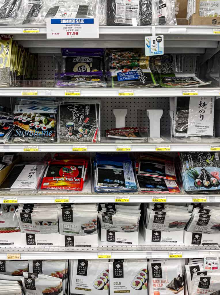 Assortment of nori seaweed packages on a grocery store shelf, showing different brands and types used for sushi and Japanese cooking.