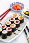 Plated maki rolls with tuna, salmon, and cucumber served with soy sauce, wasabi, and pickled ginger