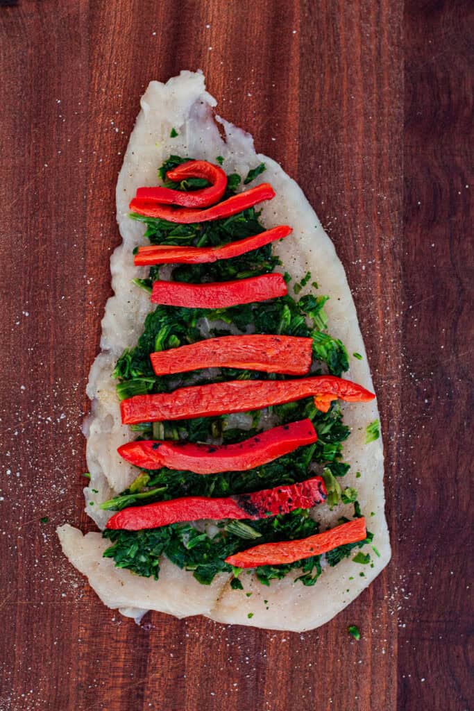 Chicken breast layered with sautéed spinach and roasted red pepper strips before rolling.