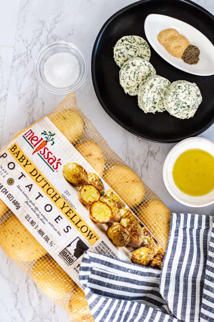 Baby Dutch yellow potatoes with herb butter, olive oil, salt, pepper, and garlic powder on a kitchen counter.
