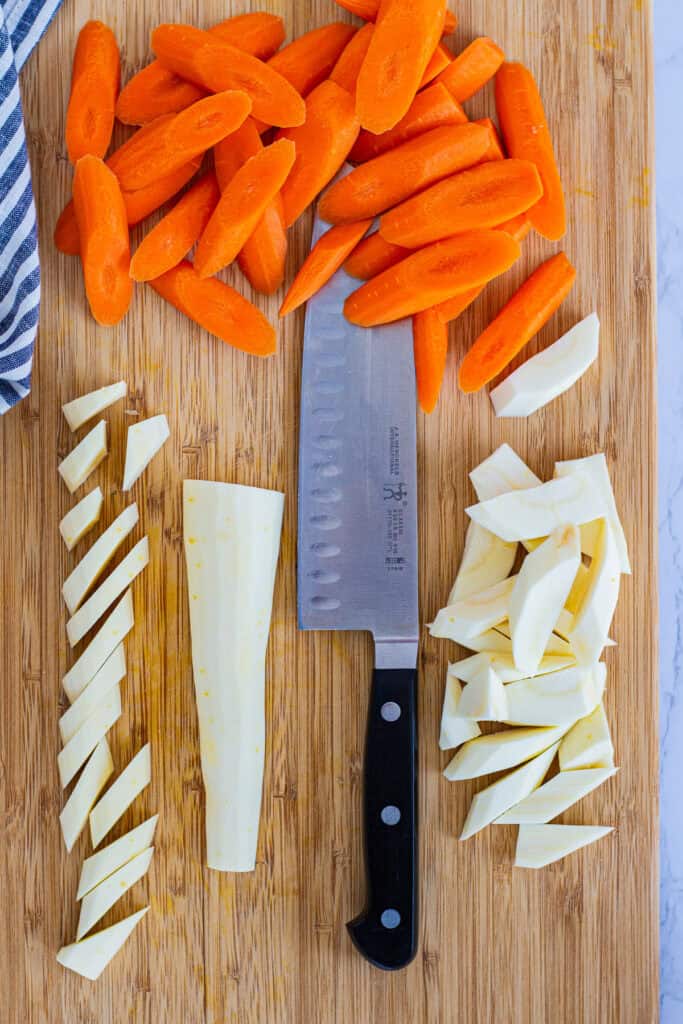 Carrots and parsnips cut into even pieces on a cutting board, ready for mixing with Moroccan spices