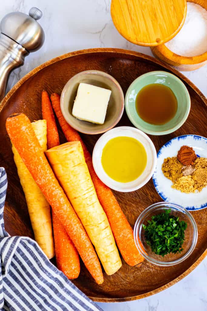 Ingredients for Moroccan roasted carrots and parsnips, including carrots, parsnips, olive oil, butter, honey, spices, and parsley
