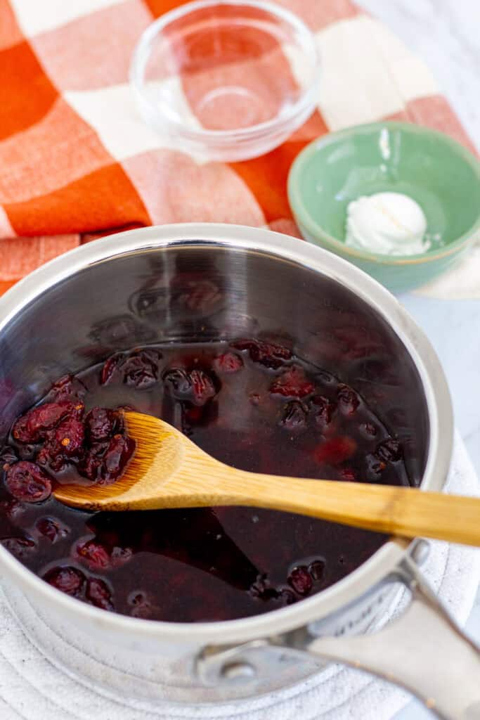 Dried cranberries simmering in a saucepan with water and pomegranate juice is the first step to making cranberry sauce with dried cranberries.