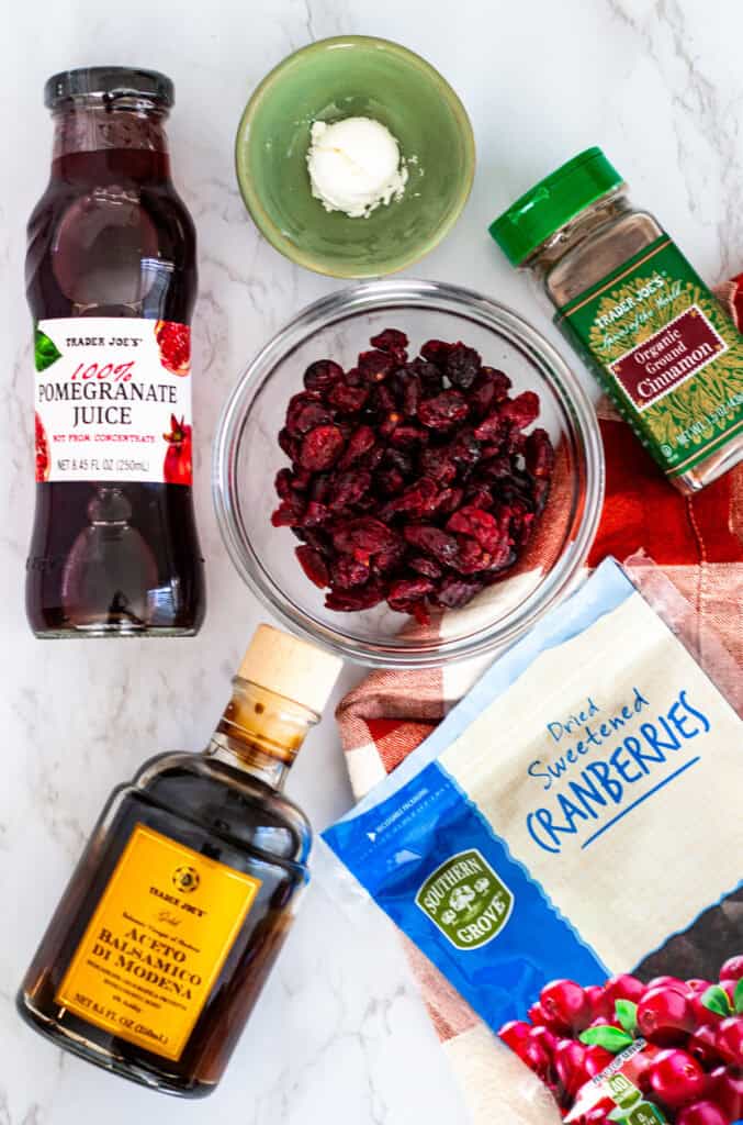 Overhead view of ingredients for cranberry sauce with dried cranberries, including dried cranberries, pomegranate juice, balsamic vinegar, cinnamon, and corn starch.