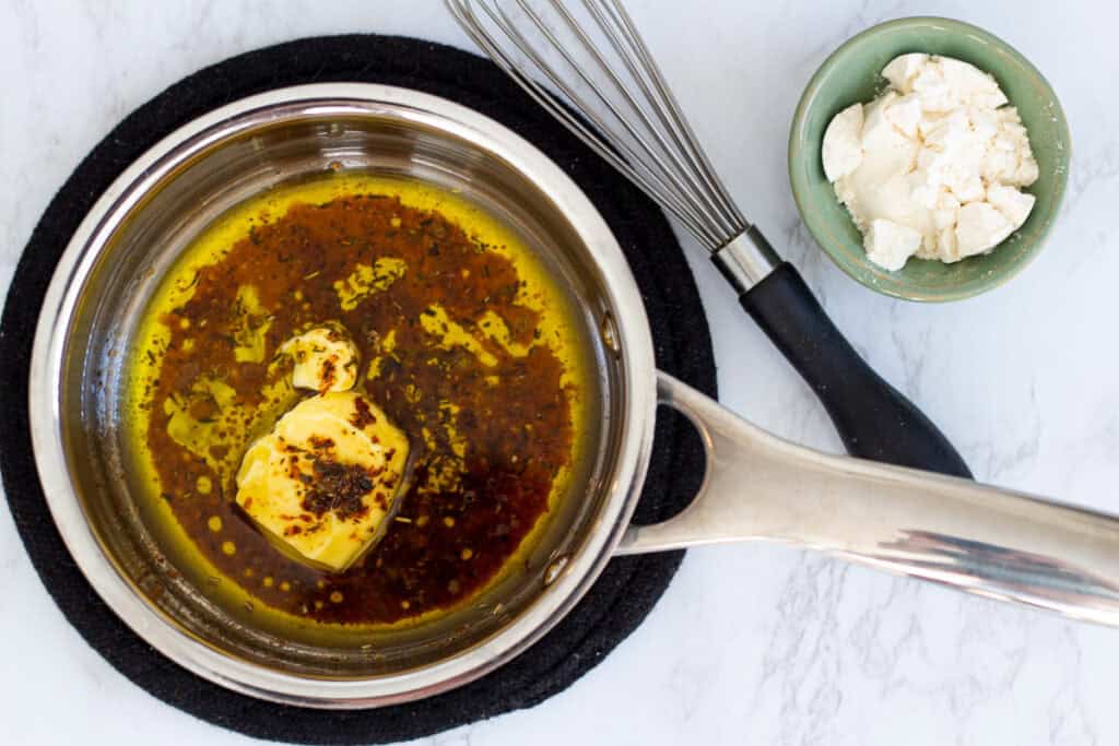 Saucepan with melted butter and chicken drippings seasoned with herbs, starting the gravy base.