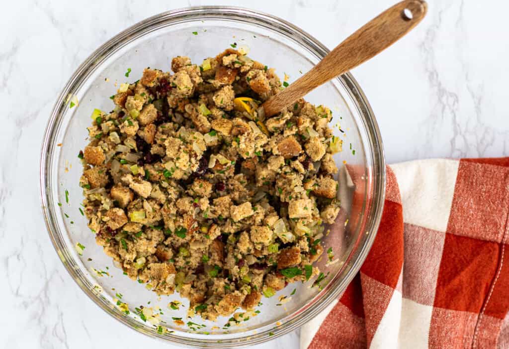 Bowl of seasoned bread stuffing with herbs and cranberries mixed together.