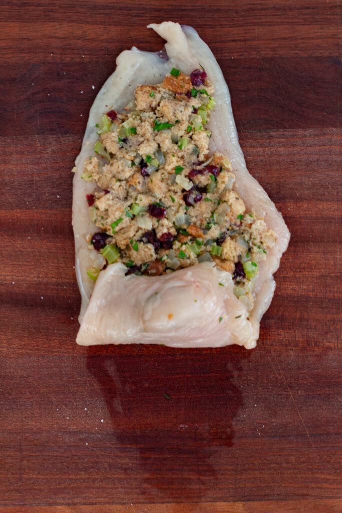 Chicken breast partially rolled up with stuffing inside, step before tying or prosciutto wrapping and baking.