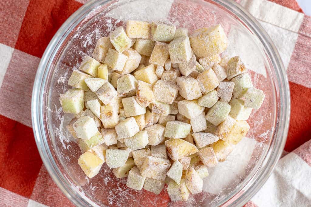 Apple cubes and candied ginger coated in flour and cinnamon for mini spiced apple cake batter
