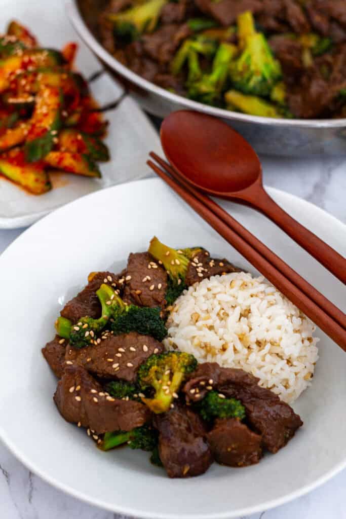Bowl of tender beef and broccoli stir fry served with rice and sesame seeds, ready to eat.