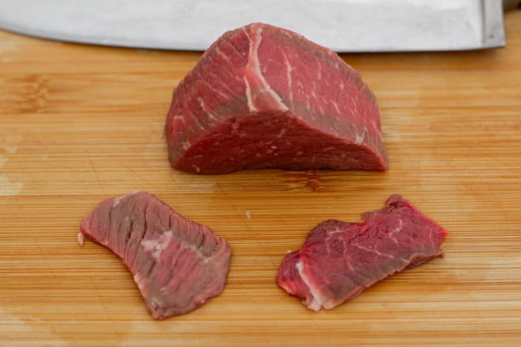 Close-up of a sliced beef piece showing visible grain lines to demonstrate how to cut against the grain.