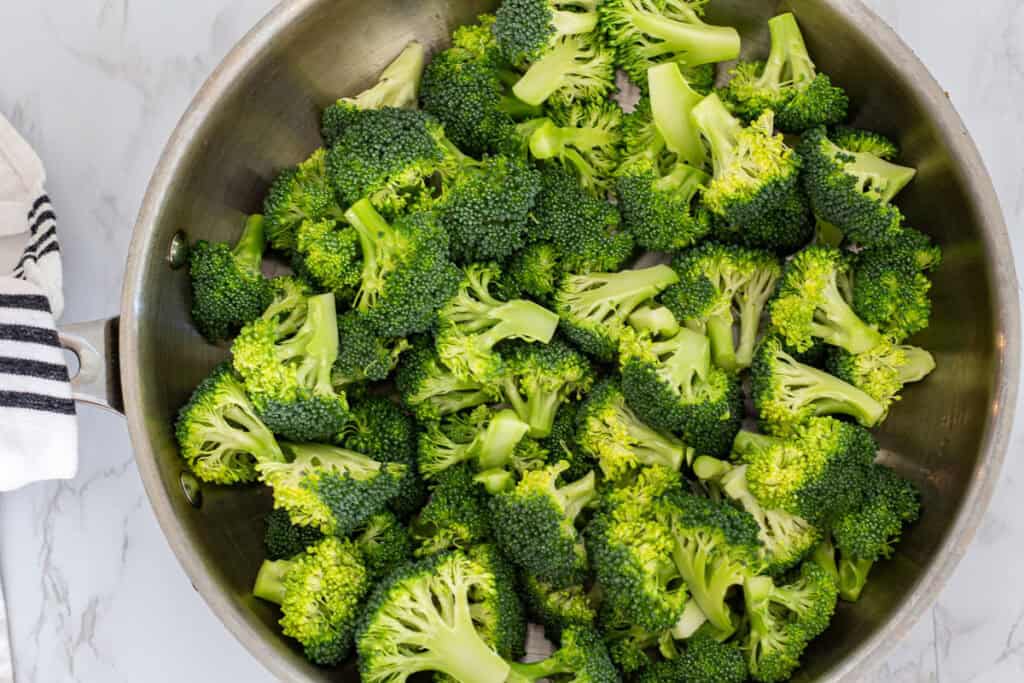 Fresh broccoli florets added to a skillet, ready to be steamed until just tender and bright green.