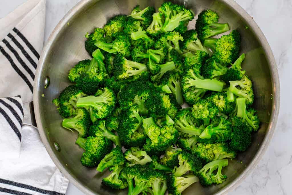 Bright green, crisp-tender broccoli in a pan after steaming, ready to be added to the stir fry.