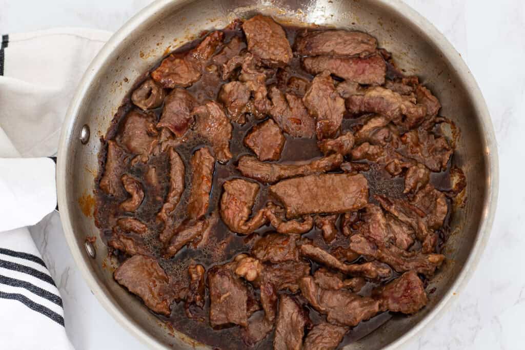 Cooked beef simmering in a rich brown sauce, soaking up flavor before adding broccoli.