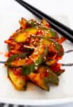 Close-up of spicy Korean cucumber salad with sesame seeds served on a plate.